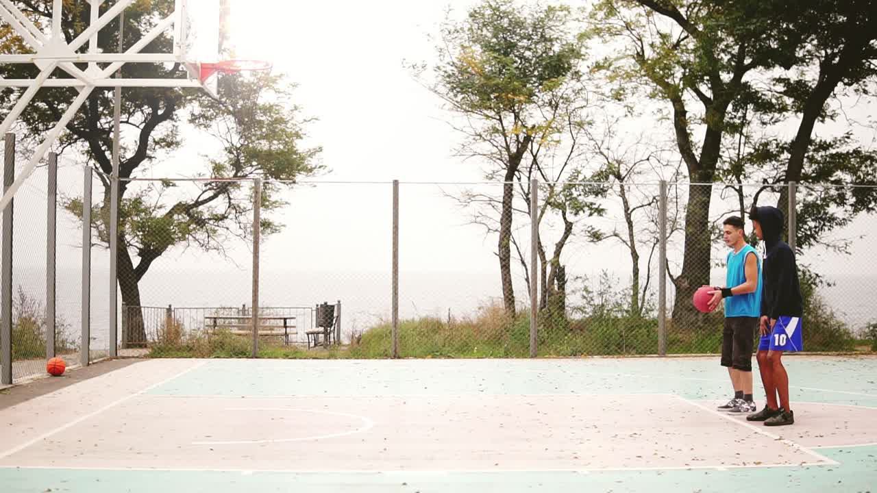 Young man teaching his friend how to throw basketball. multi ethnic friendship. Slow Motion shot