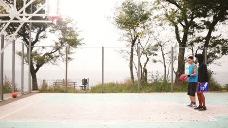 young man teaching his friend how to throw basketball. multi ethnic friendship. slow motion shot