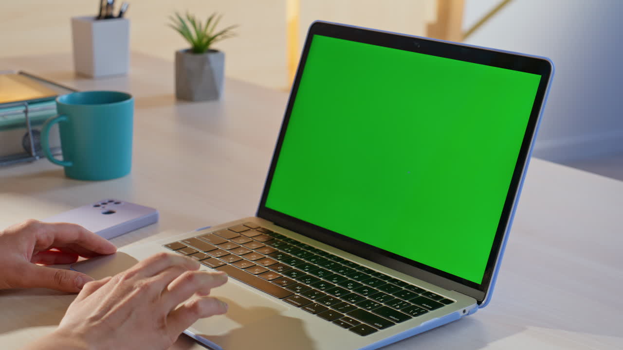 Typing on a laptop with a green screen