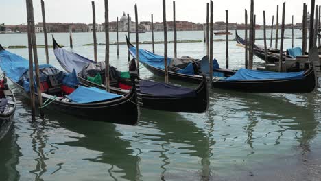 Moored-gondola-boats-parked-along-the-Grand-Canal-on-a-beautiful-morning-in-Venice,-Italy