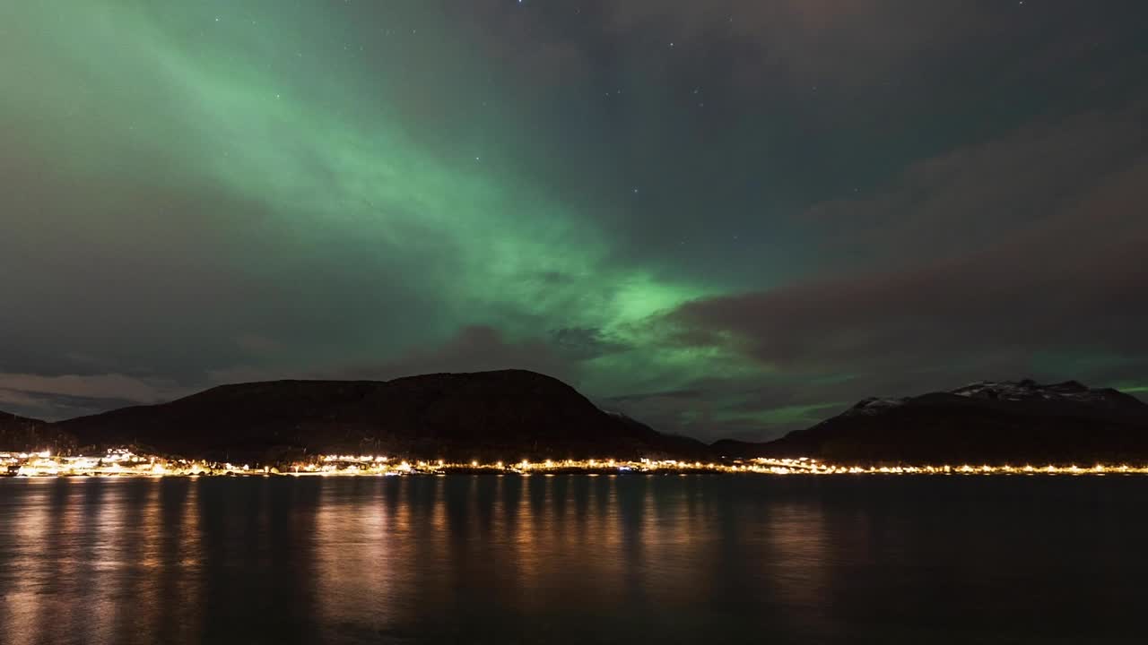 el lapso de tiempo de las auroras y la costa iluminada de la ciudad de tromsø al anochecer, noruega