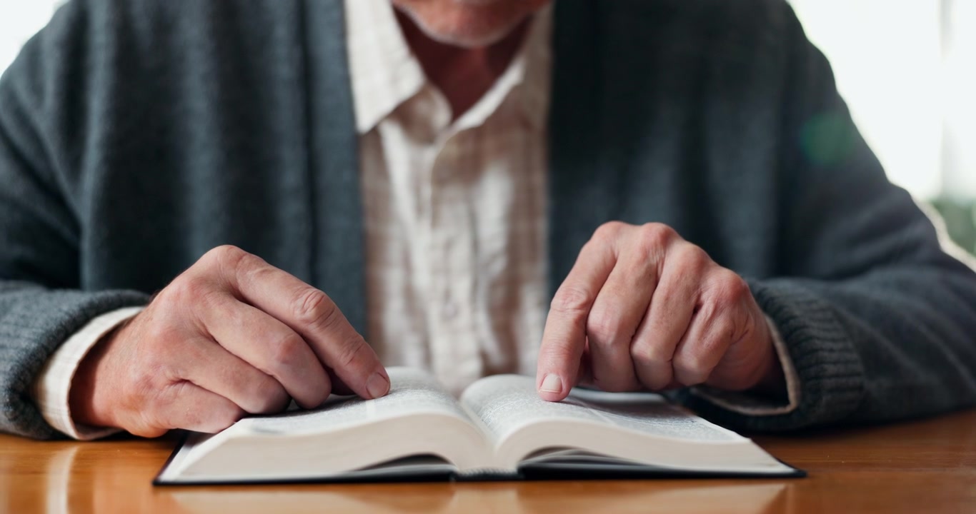 Uomo anziano che legge un libro a un tavolo