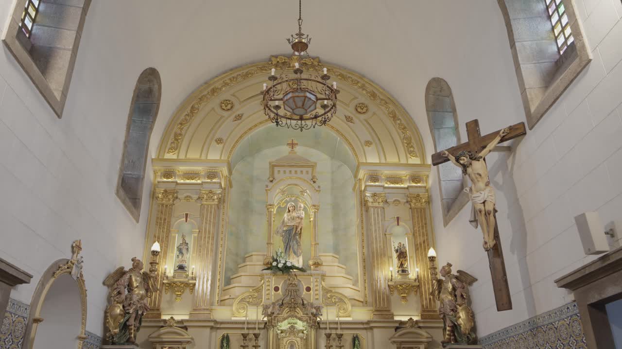 Interno di una chiesa cattolica ornata che mostra l'altare con la statua della Vergine Maria, il crocifisso e il lampadario