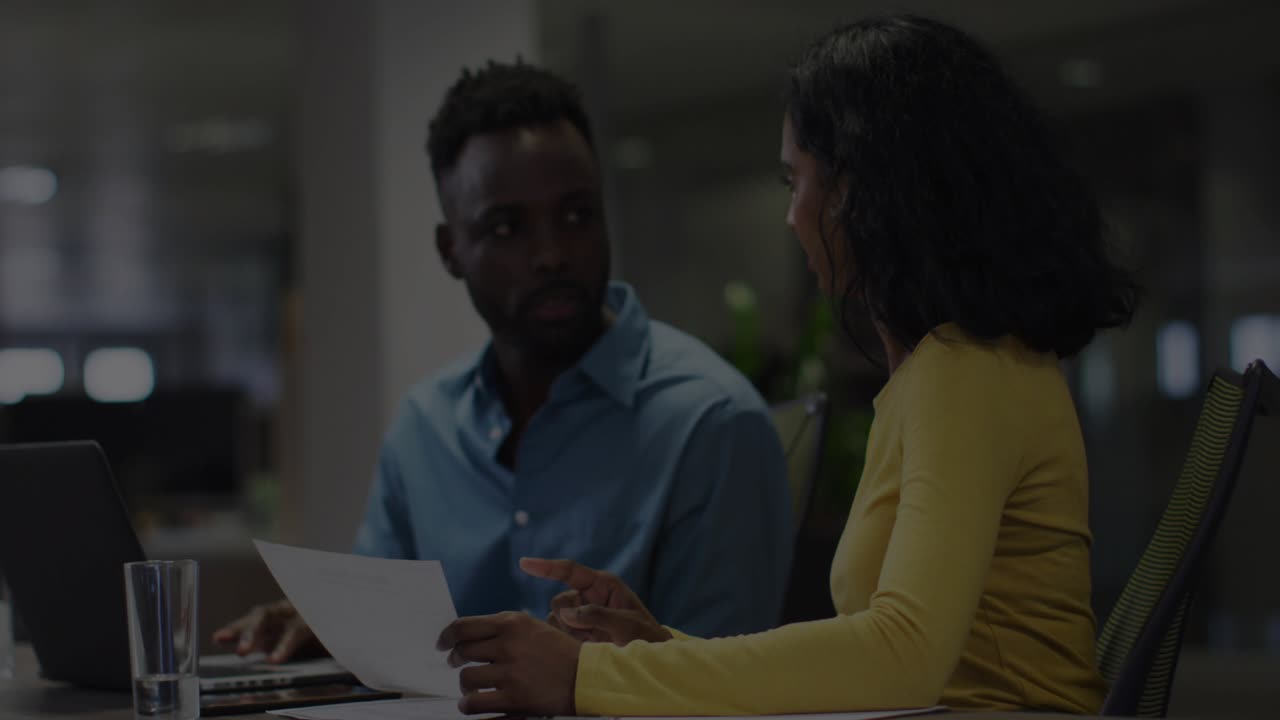 Man typing on laptop and woman analyzing data in business meeting initiating data overlay flashing