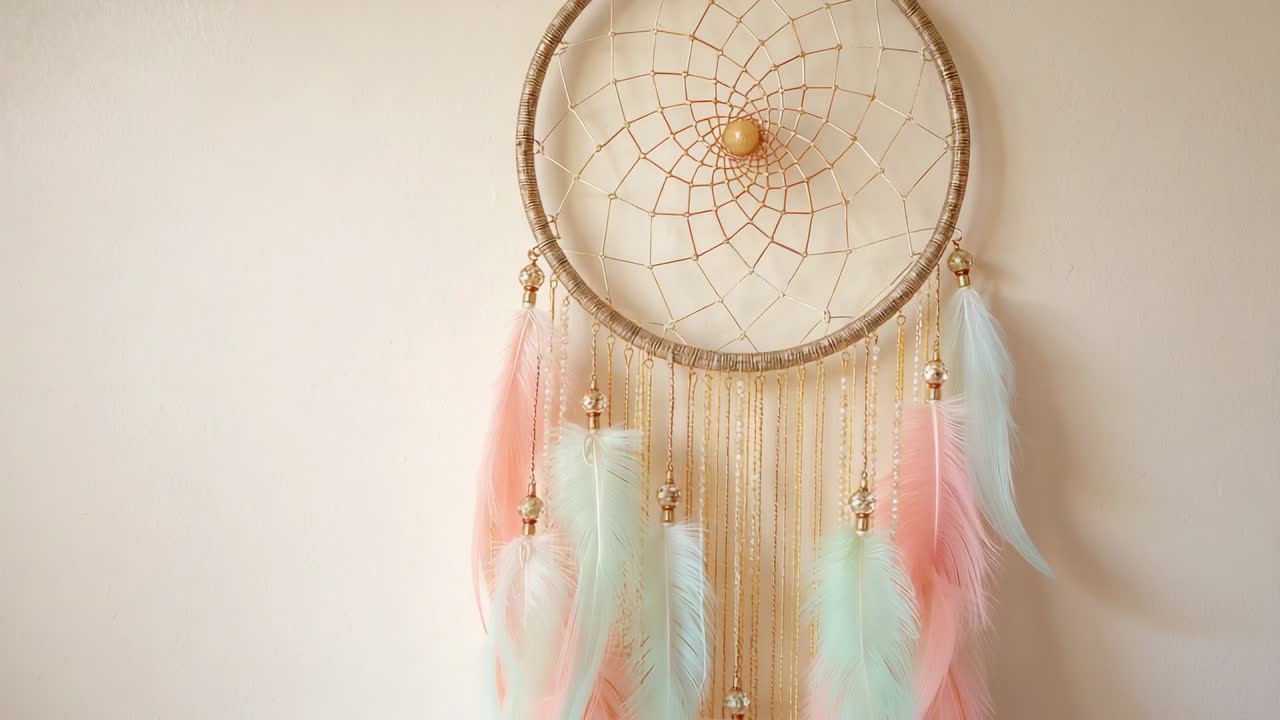 Hanging gold hoop dreamcatcher showcasing web pastel pink or mint or blue feathers against beige wal