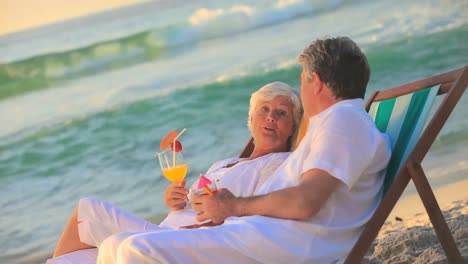 mature couple drinking cocktails in deckchairs