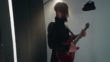 dynamic shot of a guitarist in black playing a red electric guitar against a plain white background with active camera zooming