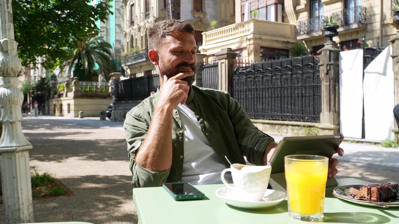 Uomo che lavora al tablet in un caffè all'aperto.