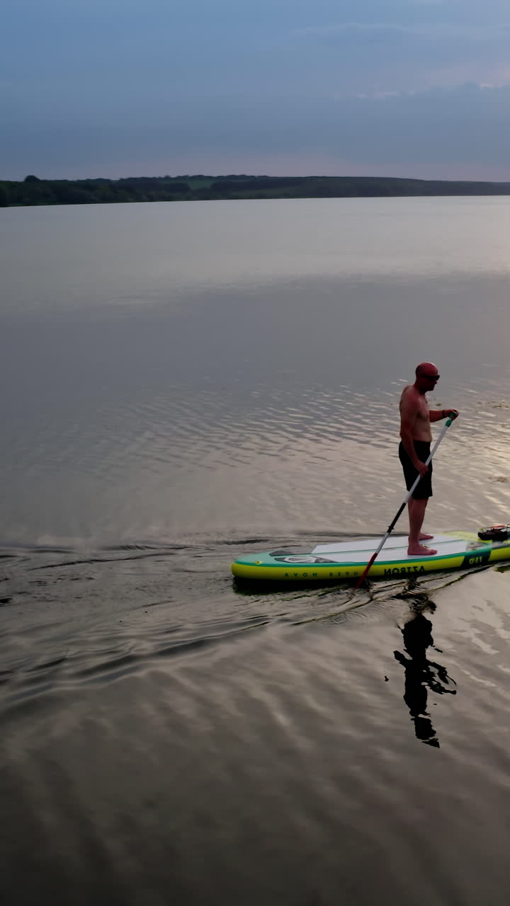 Man standing on paddle board. Aerial view of man paddling on SUP board on large river