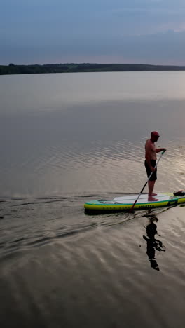 man standing on paddle board. aerial view of man paddling on sup board on large river