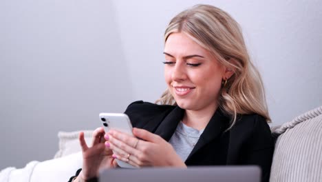 una joven empresaria se sienta en el sofá y navega en su teléfono celular de cerca