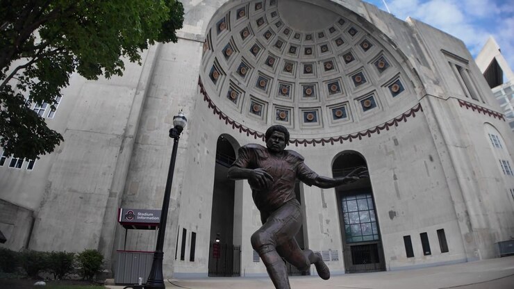 Statua di Archie Griffin all'Ohio Stadium presso l'Università dell'Ohio a Columbus, Ohio, con nuvole bianche e un cielo blu.