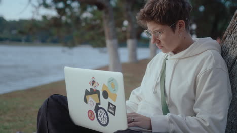 young woman studying online with laptop in the park