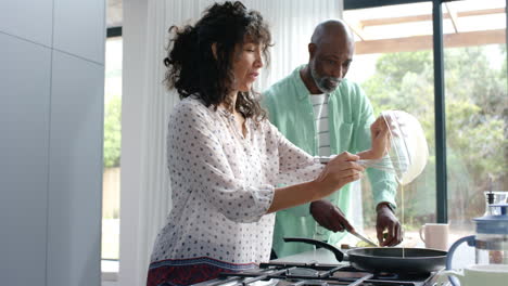 Happy-biracial-couple-preparing-eggs-for-breakfast-in-kitchen,-slow-motion