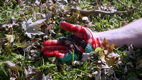 Assault-concept,-Isolated-bloody-male-hand-falls-on-grass-ground,-Sunny-day