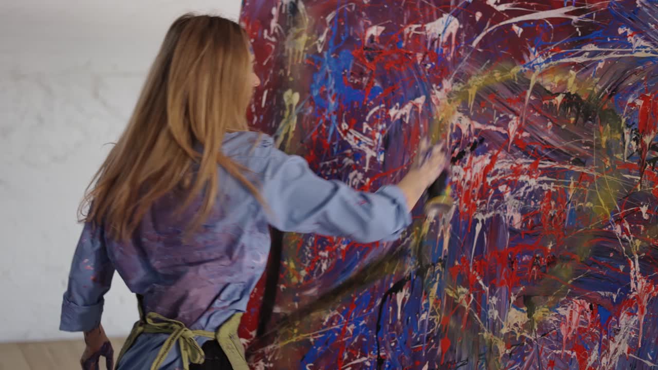 Artista feminina desenha em uma grande tela colorida com uma imagem abstrata da palavra 'amor'.