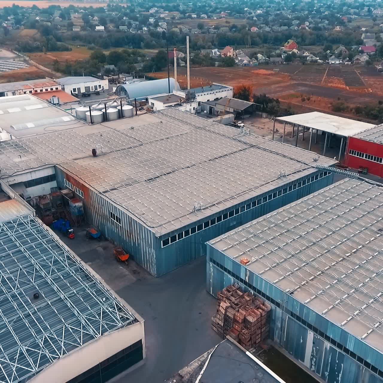 Large premises at warehouse area. Constructions for storage building materials outside the city. Farmlands at backdrop