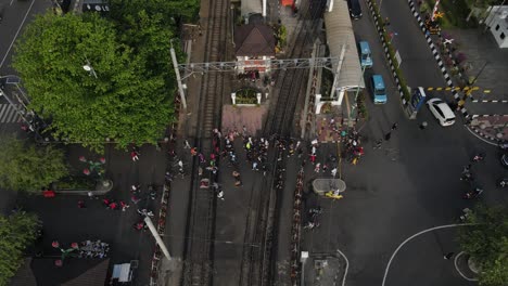 aerial footage, pedestrians passing through a railroad crossing barrier to cross, located at the malioboro railway crossing, tugu station, yogyakarta.