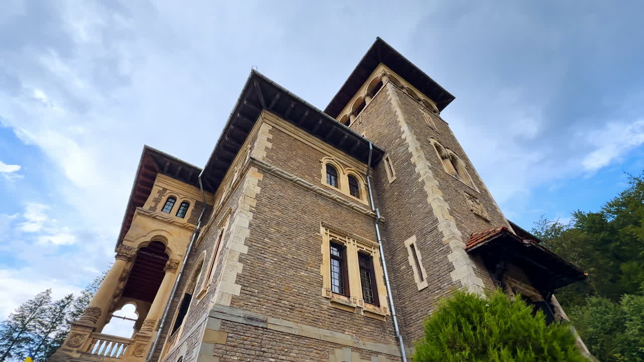 Grey brick walls of Cantacuzino Castle on rainy day. Low angle view at the landmark of Romania against cloudy sky