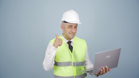 engineer holding laptop laughing at camera.