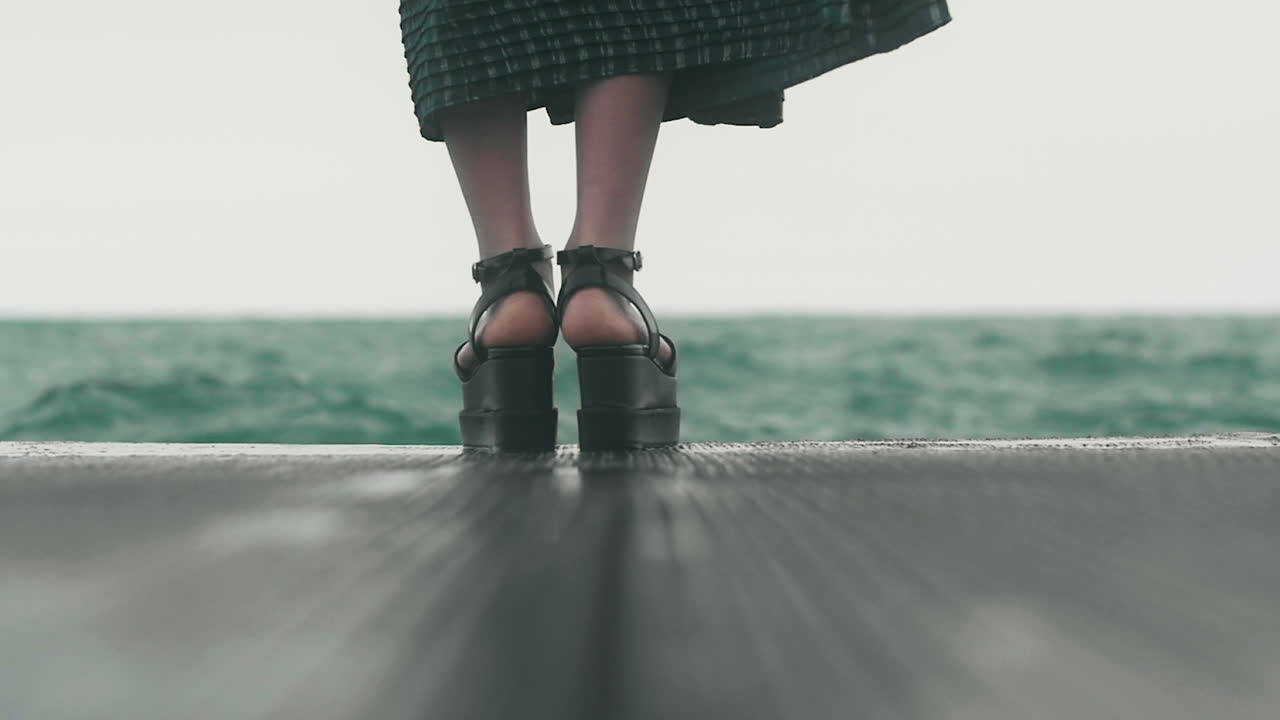 Along the Blue-Green Lake, a woman walks in her tall black shoes and emerald green dress. Asian fashion style against the eerie green water of Lake Michigan
