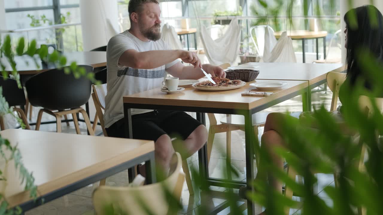 una pareja comiendo pizza en un café moderno