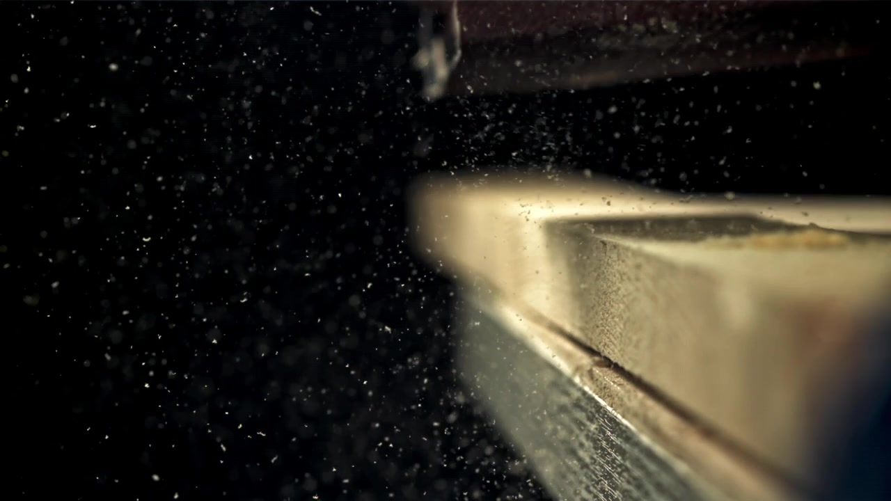 Detailní záběr ruky brousící dřevo s létajícími pilinami zpomaleně