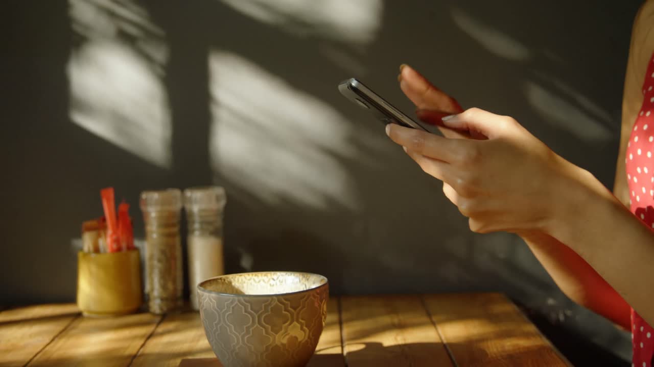 Vista laterale di donna di etnia mista che usa il cellulare in un caffè 4k