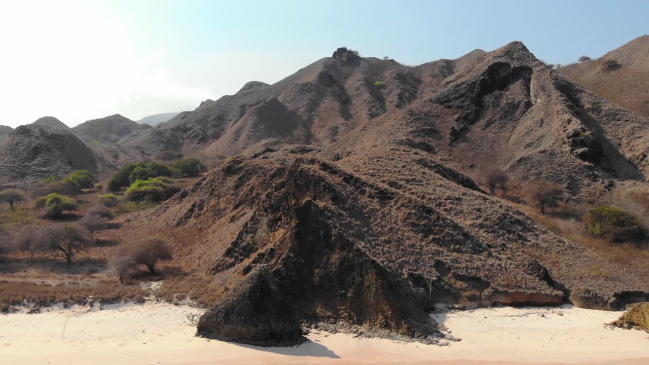 인도네시아 코모도 국립공원 (komodo national park) 에 있는 파드 섬의 분홍색 해변에 있는 가파른 산과 푸르키즈색 물.