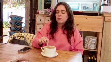 thoughtful woman mixing her coffee while unwinding