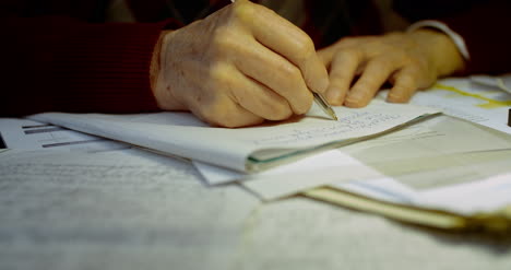 Senior-Businessman-Writing-On-Paper-At-Table-In-Office-25