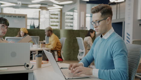 coworking office scene with diverse team working on laptops