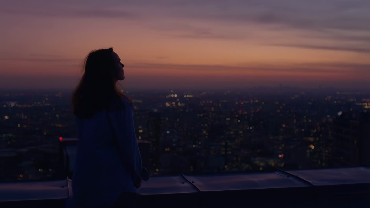 Person Silhouetted Against Sunset Over City Rooftop
