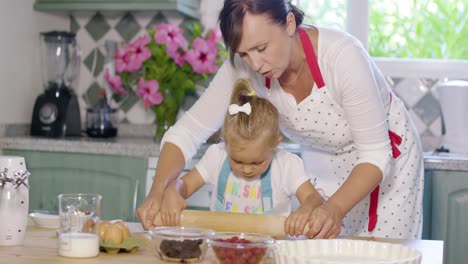 mother rolling out pastry with a little helper