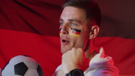 feliz partidario de fútbol masculino caucásico con la bandera de alemania sobre la iluminación rosada