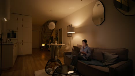 woman working on laptop in cozy living room at night