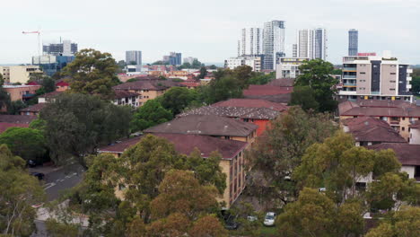 Aerial-drone-shot-ascending-slowly-over-trees-to-reveal-the-city-of-Liverpool,-Sydney-Australia