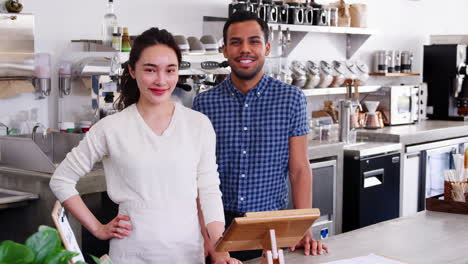 young mixed race couple coffee shop owners looking to camera