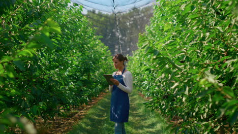 Woman-farmer-collecting-data-with-modern-device-in-green-plantation-smiling