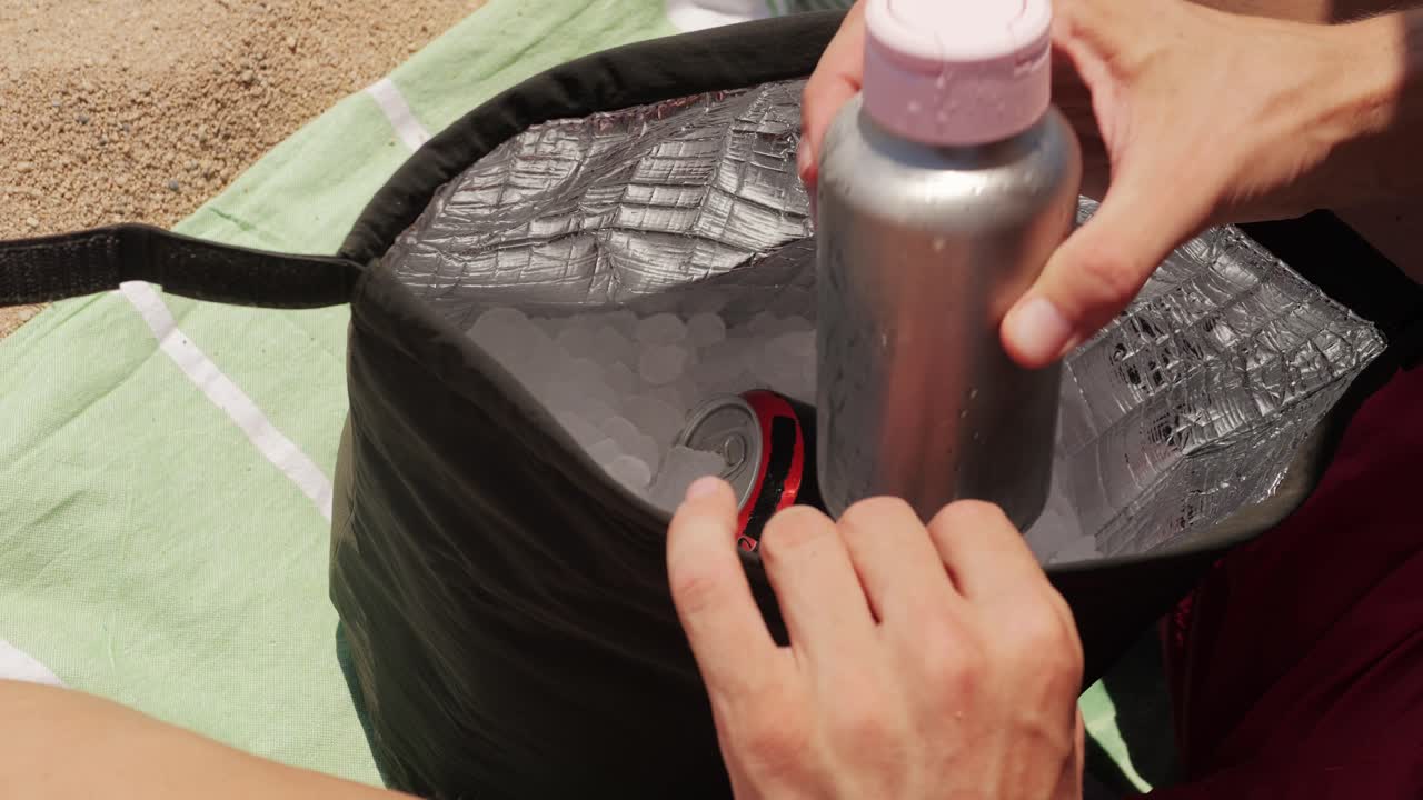 Person Putting Drinks and Food into Cooler on the Beach
