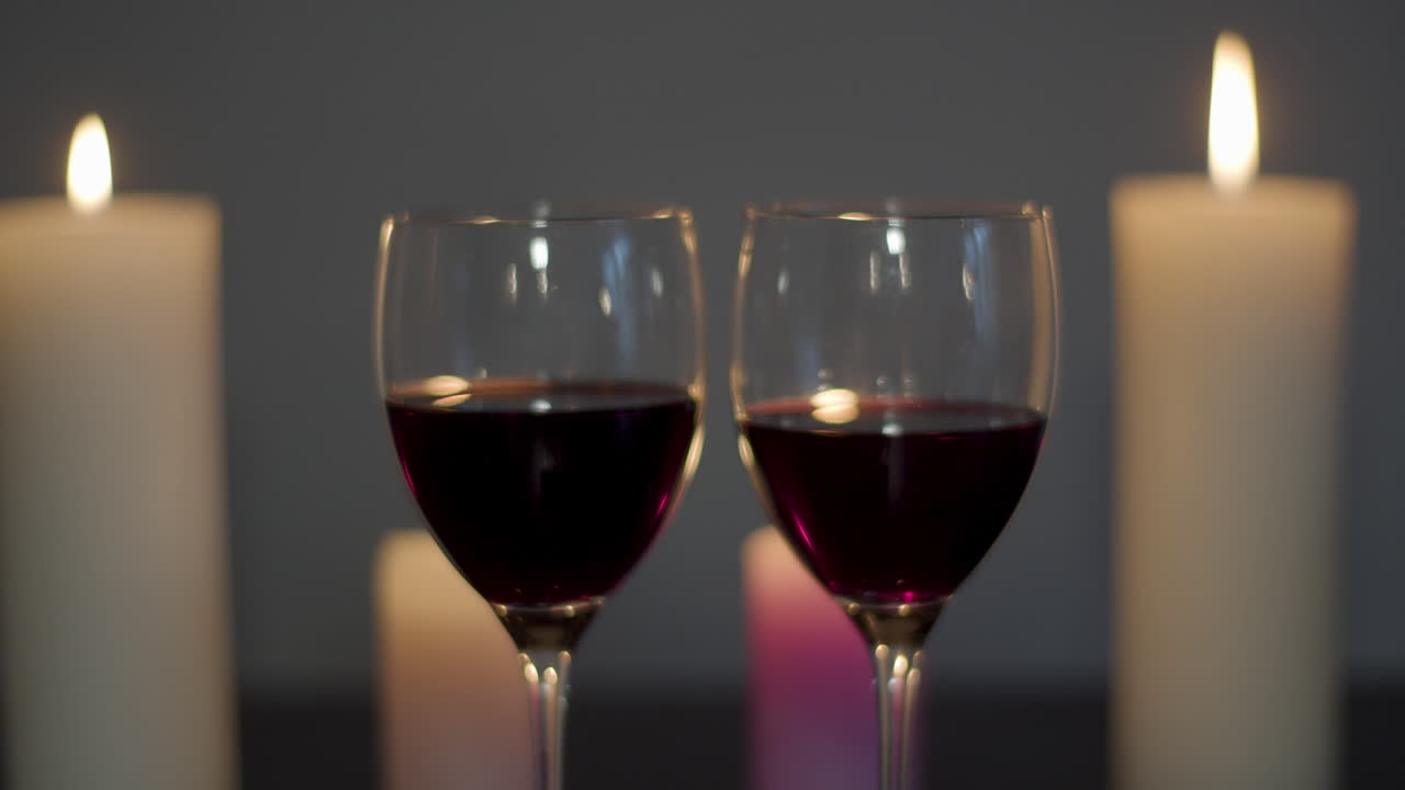 Dolly in of two glasses of wine on a candle lit table - starting wide to close