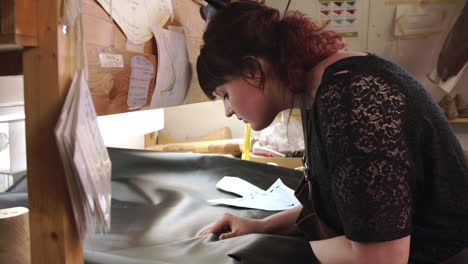 bespoke shoemaker measuring and cutting leather for shoe