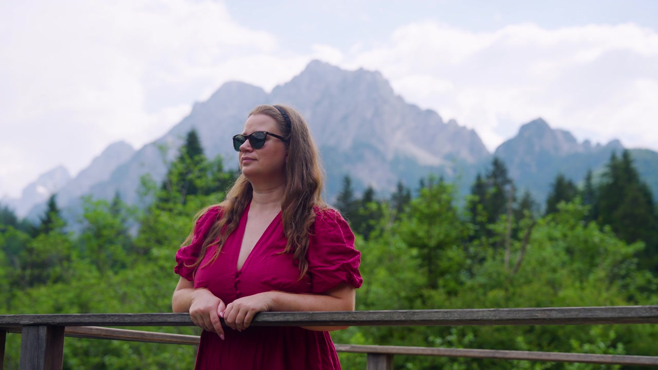 Female Traveler In A Red Dress Explores The Scenic Landscape Of Zelenci Nature Reserve In Slovenia. Close-up Medium Shot
