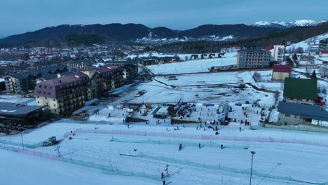 an aerial view of a winter resort town, featuring snow-covered buildings and streets in a picturesque setting