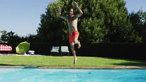 hombre caucásico divirtiéndose saltando a una piscina