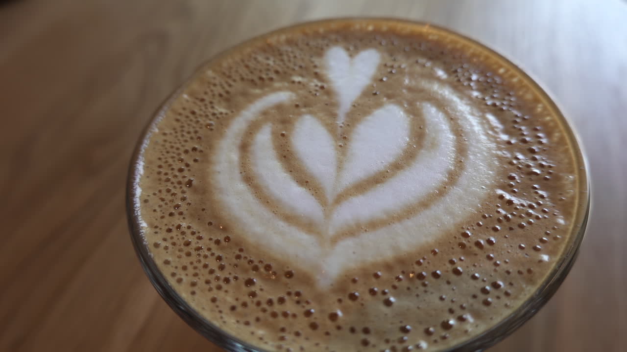 Close up of a glass of latte on a wooden table at a cafe