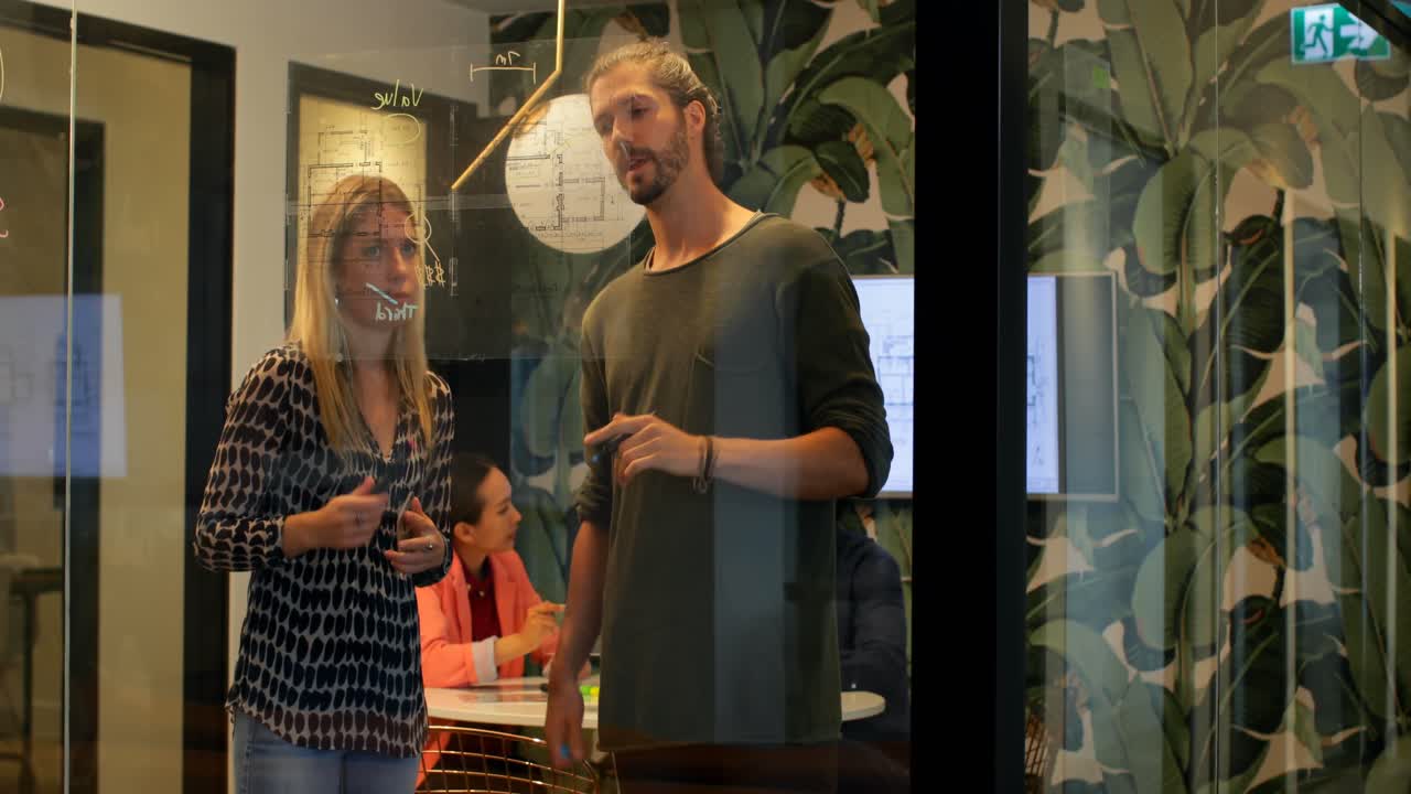 Colegas de trabalho discutindo em quadro de vidro no escritório 4k