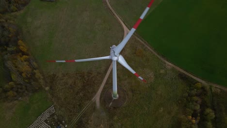 toma aérea de una turbina eólica giratoria con bordes rojos para la producción de energía eléctrica renovable en un campo en 4k