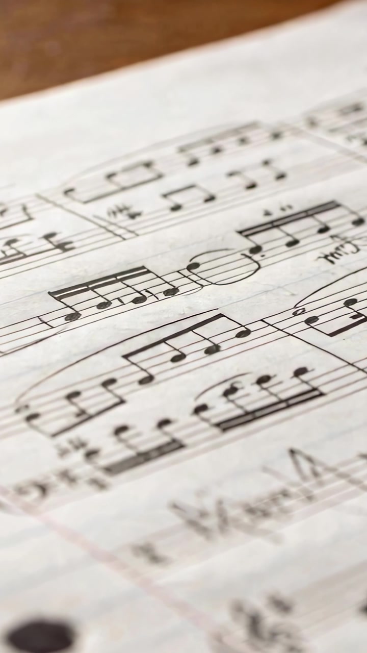 Vertical video: Shifting camera revealing music sheet on desk for study, showing beamed notes, hole