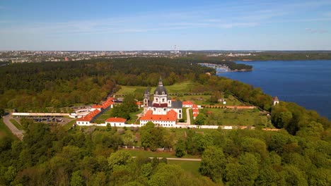 aerial shot of old pazaislis monastery and church and forest on sunny day with blue clear sky, in kaunas, lithuania, parallax shot